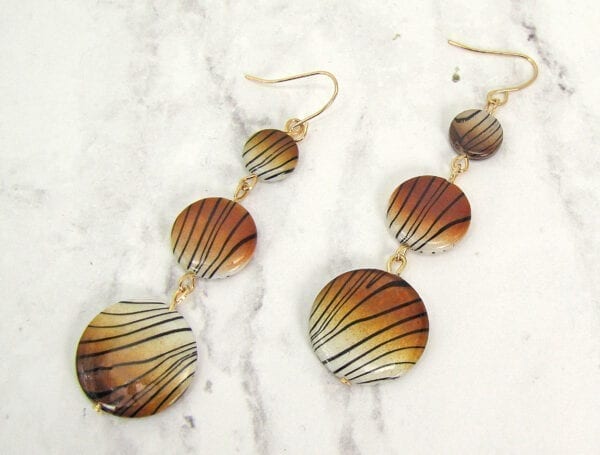 earrings with tiger-print pendants on a marble surface