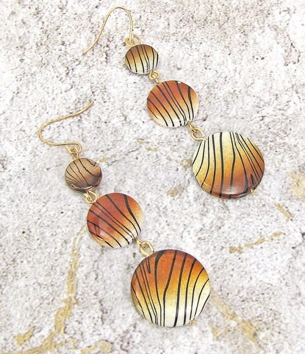 earrings with tiger-print pendants on a concrete surface