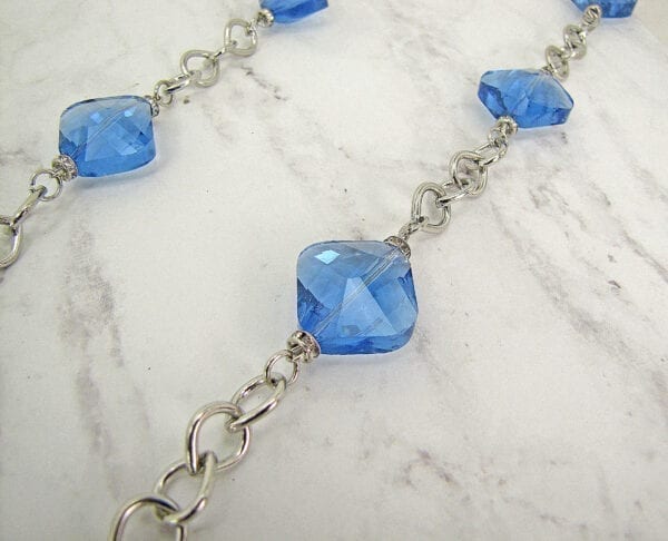 silver chain necklace with light blue gemstones on marble stones
