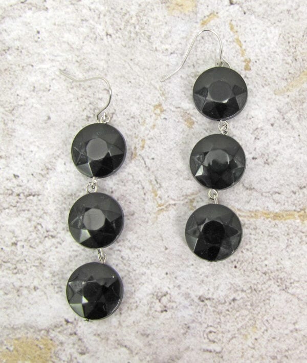 earrings with columns of black crystals on a concrete surface