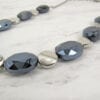 necklace with black crystals and metallic beads on a marble surface