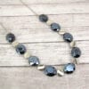 necklace with black crystals and metallic beads on a wooden surface