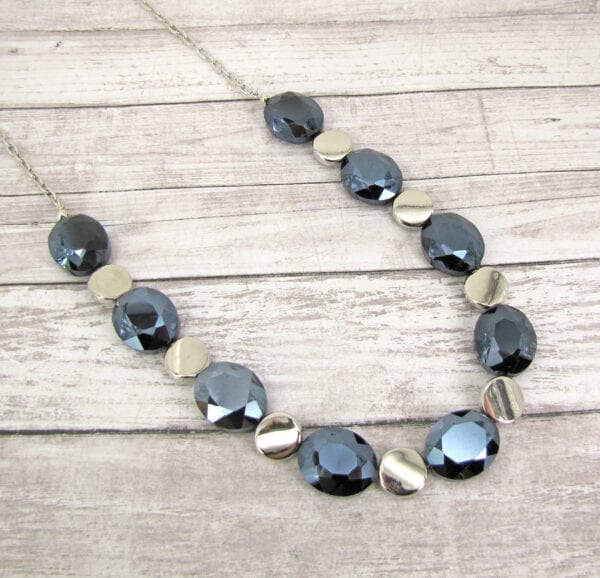necklace with black crystals and metallic beads on a wooden surface