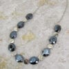 necklace with black crystals and metallic beads on a concrete surface