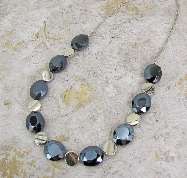 necklace with black crystals and metallic beads on a concrete surface