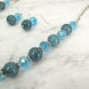 segment of necklace with blue stones and crystals on a marble surface