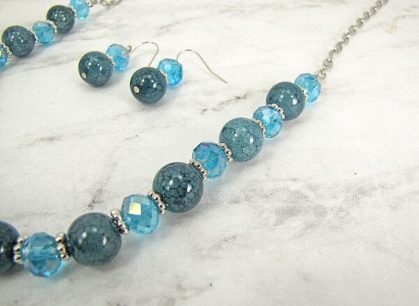 segment of necklace with blue stones and crystals on a marble surface
