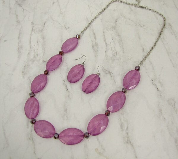 necklace and earrings with large oval violet beads on a marble surface
