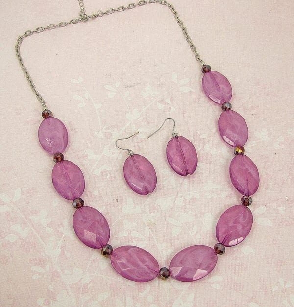 necklace with large oval violet beads on a pink cloth surface