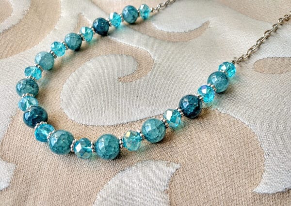 necklace with blue stones and crystals on a cloth surface