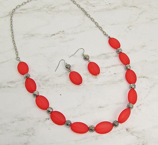 necklace and earrings with large red oval beads on a marble surface