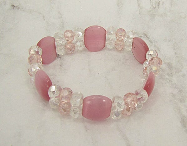 close up of a bracelet with pink stones and crystals on a marble surface