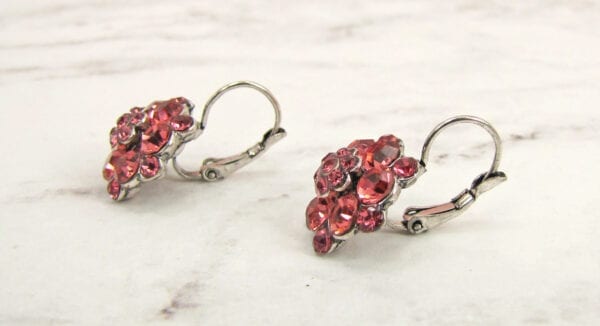 side view of earrings with ruby gems arranged like flowers on a marble surface