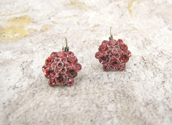 front view of earrings with ruby gems arranged like flowers on a marble surface
