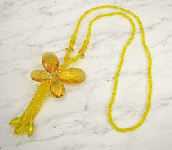 Necklace with yellow crystals in a butterfly design on marble surface