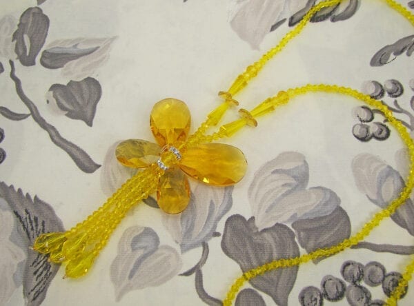 Close up of a necklace with yellow crystals in a butterfly design on a decorated surface