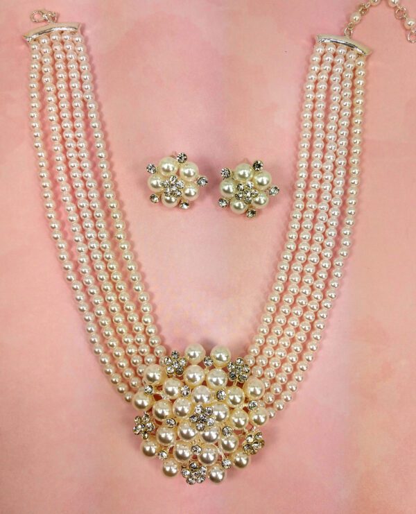 layered pearl necklace and earrings on a pink surface