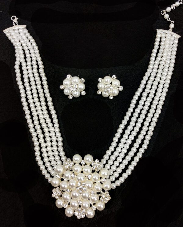 layered pearl necklace and earrings on a velvet black surface